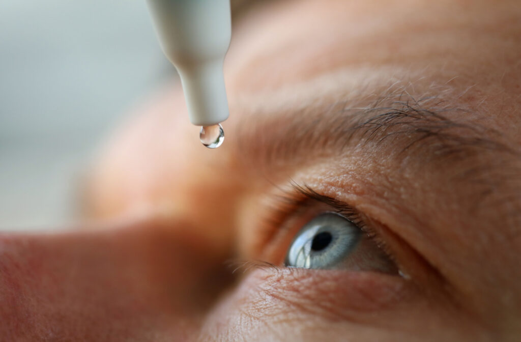 A close-up of a man using eye drops.