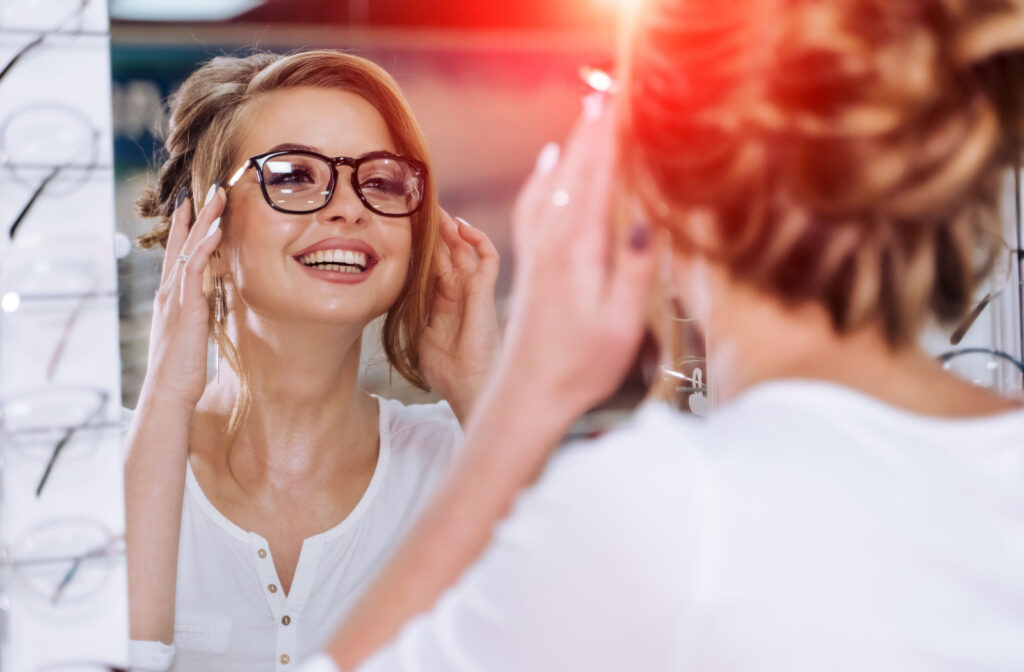 A woman trying on glasses in front of a mirror at an optometry office.