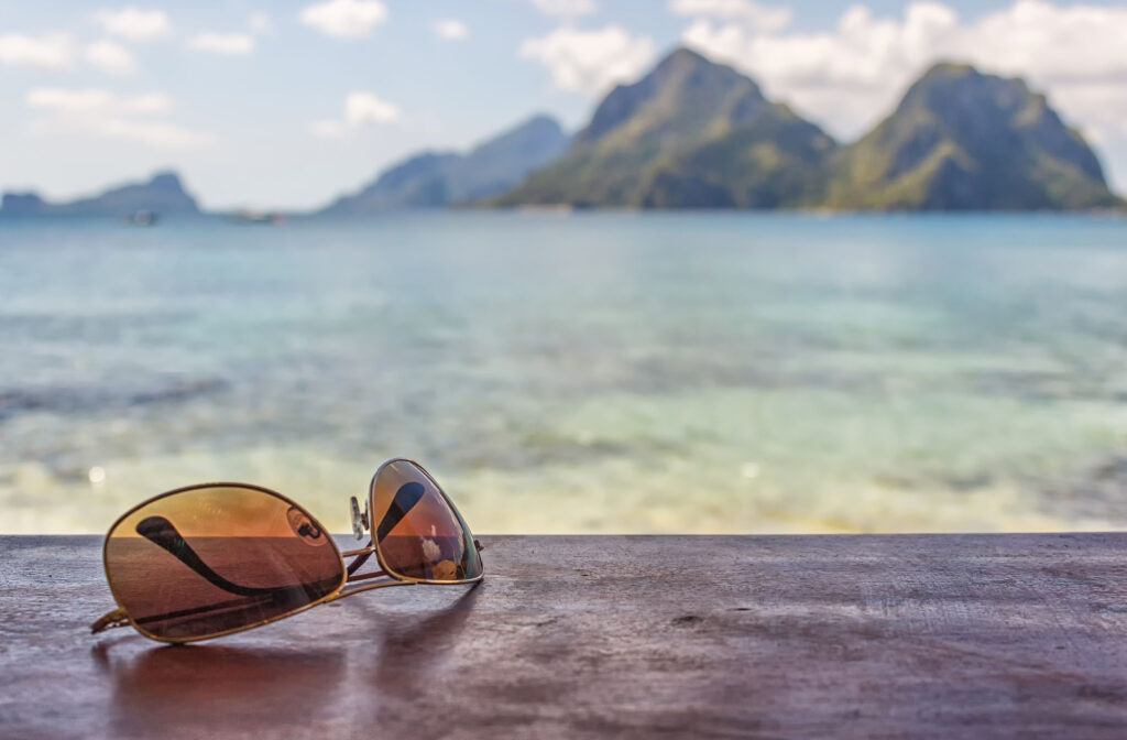 Polarized sunglasses sitting on a table with a beach in the background