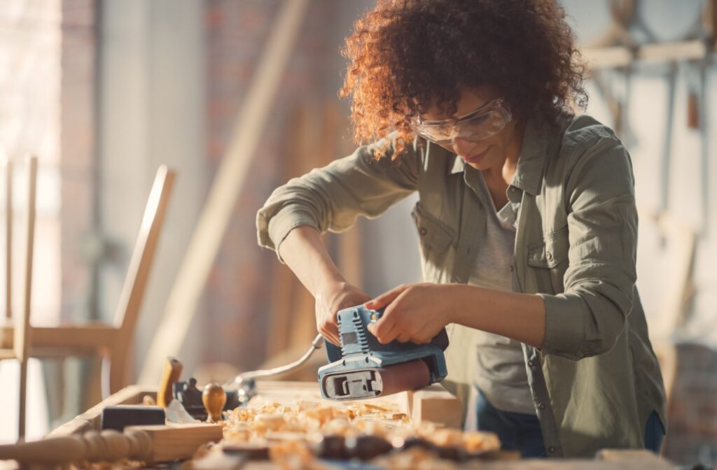 A woman is working on carpentry with her prescription safety glasses.