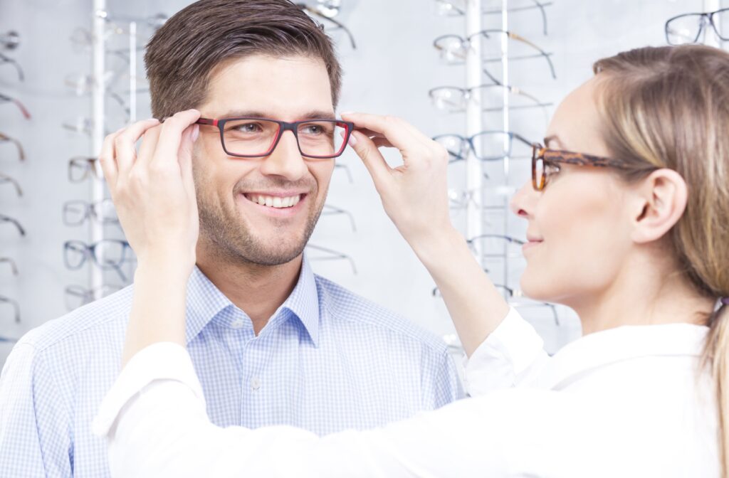 A female eye doctor assists her patient with trying on a new pair of eyeglasses