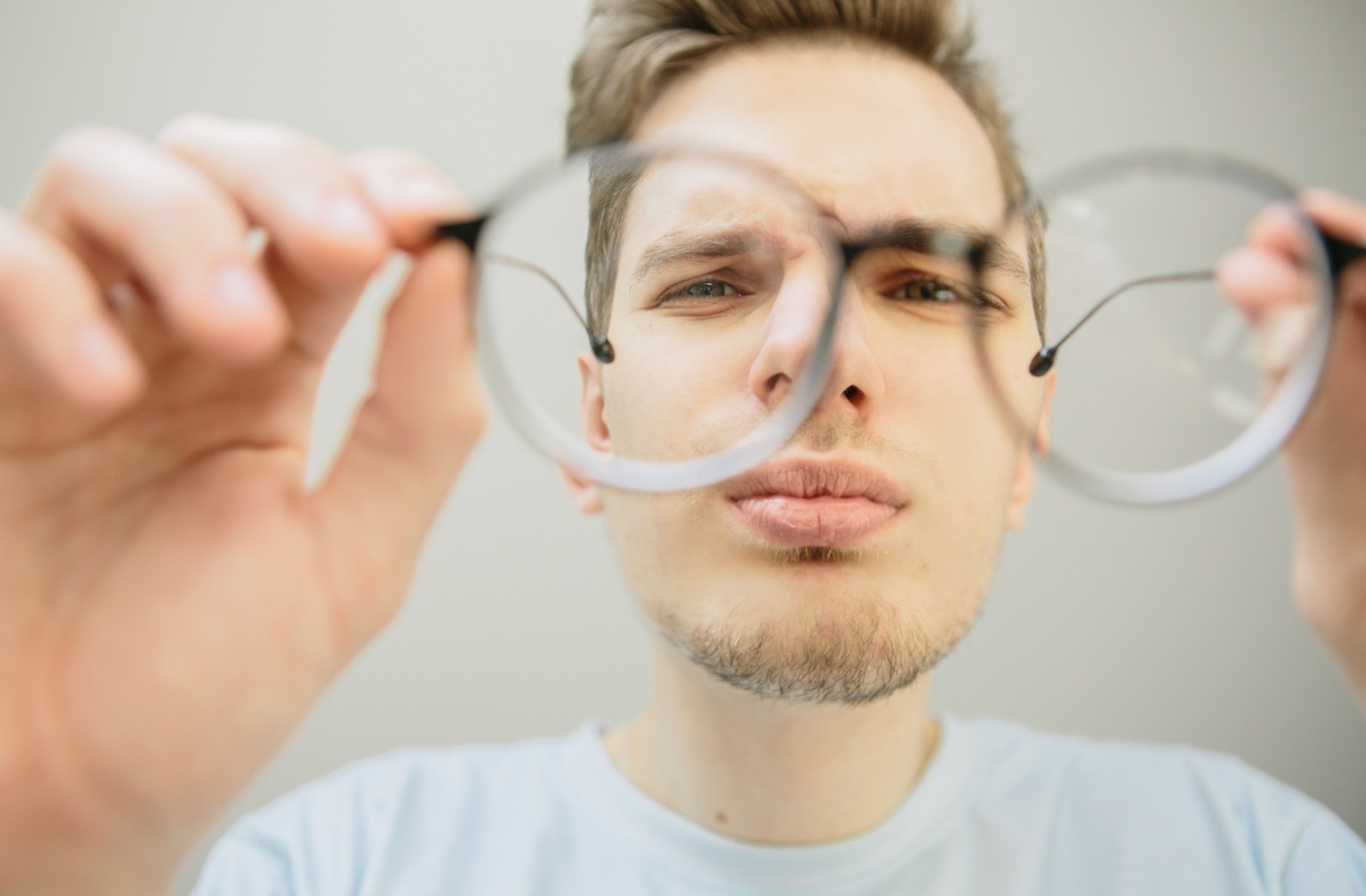 A man looks through his glasses and inspects the lens to determine its shape, convex or concave