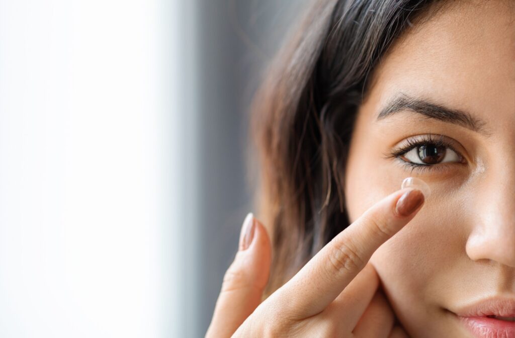 A close-up of a young woman inserting her contact lens.