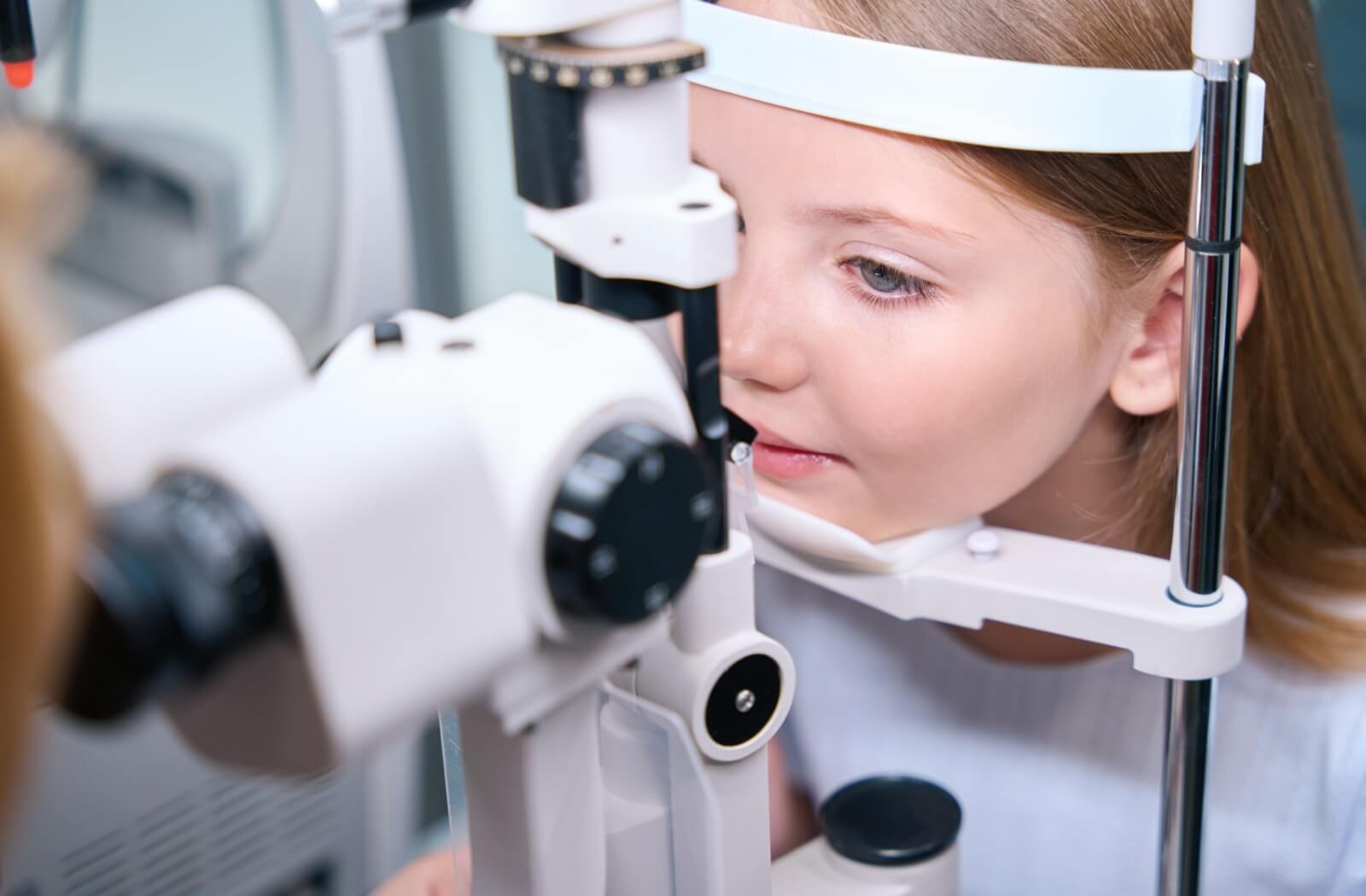 A child has their eye examined by an optometrist during an eye exam.
