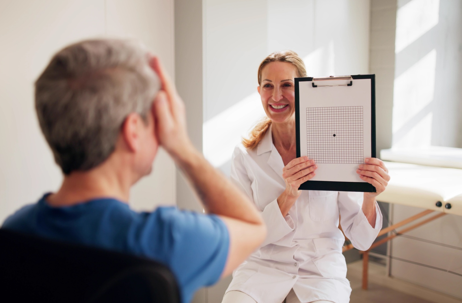 A man covering one eye undergoing an eye test for Macular Degeneration
